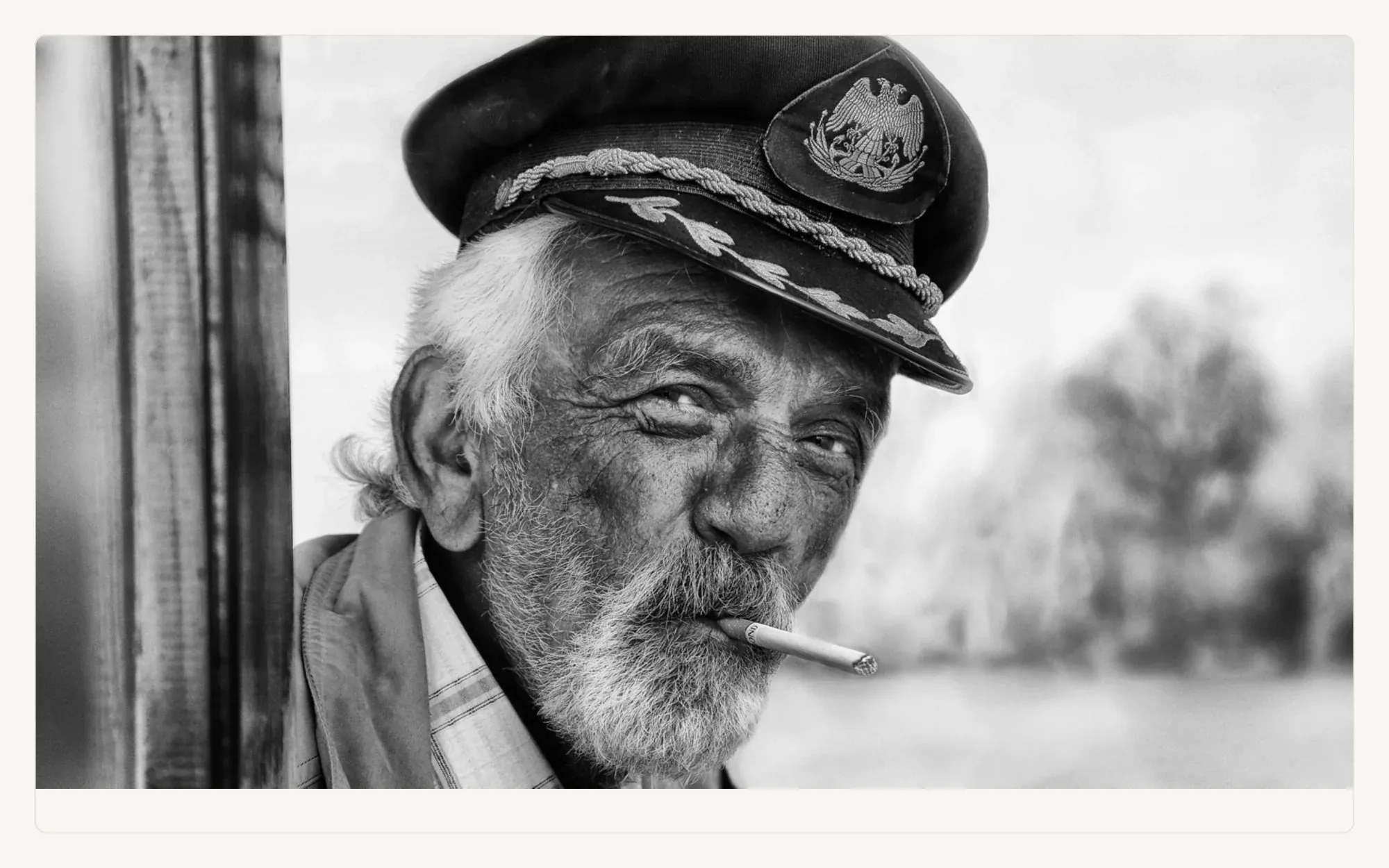 A black and white portrait by Jan Valo of an older man in a captain's cap.